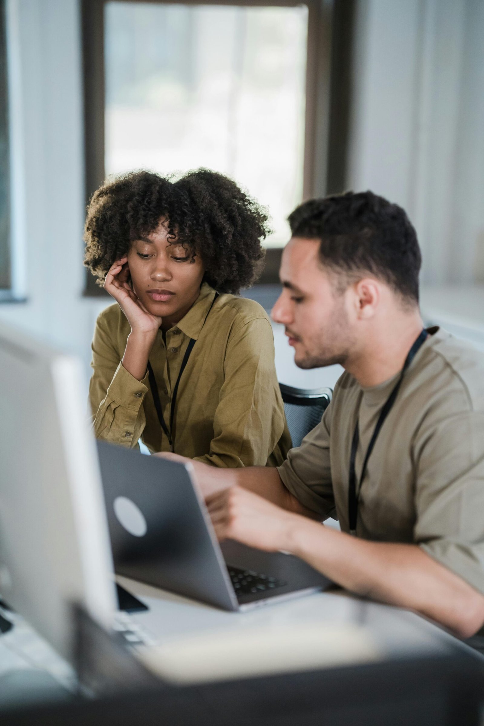 Two colleagues collaborating in a modern office setting, engaged in discussion.