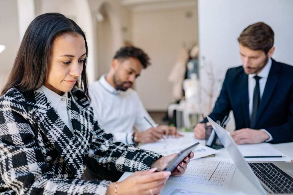 End-to-End Payroll Services | Full Service Payroll Provider Guide Professionals collaborating in a modern office, focusing on a tablet and taking notes.